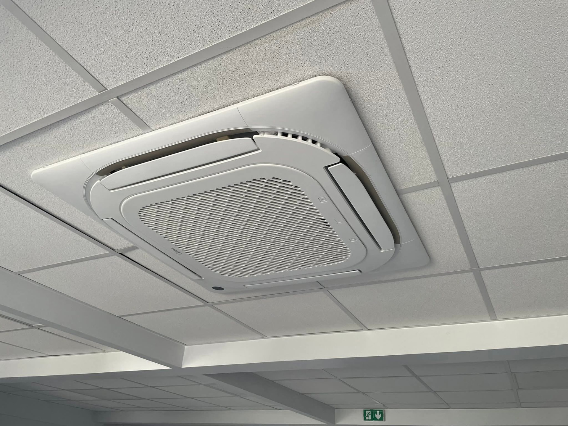 Installation – Lamentin – climatisation Martinique Cassette de plafond Midea intégrée à un faux-plafond à ossature apparente dans des locaux professionnels du Lamentin, panneau d'évacuation en partie basse – Lamentin, Martinique – LD CLIM 972